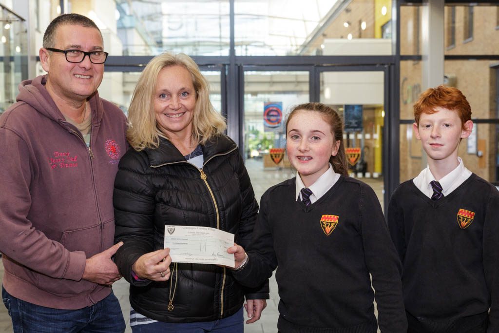 Student hand a cheque over to charity