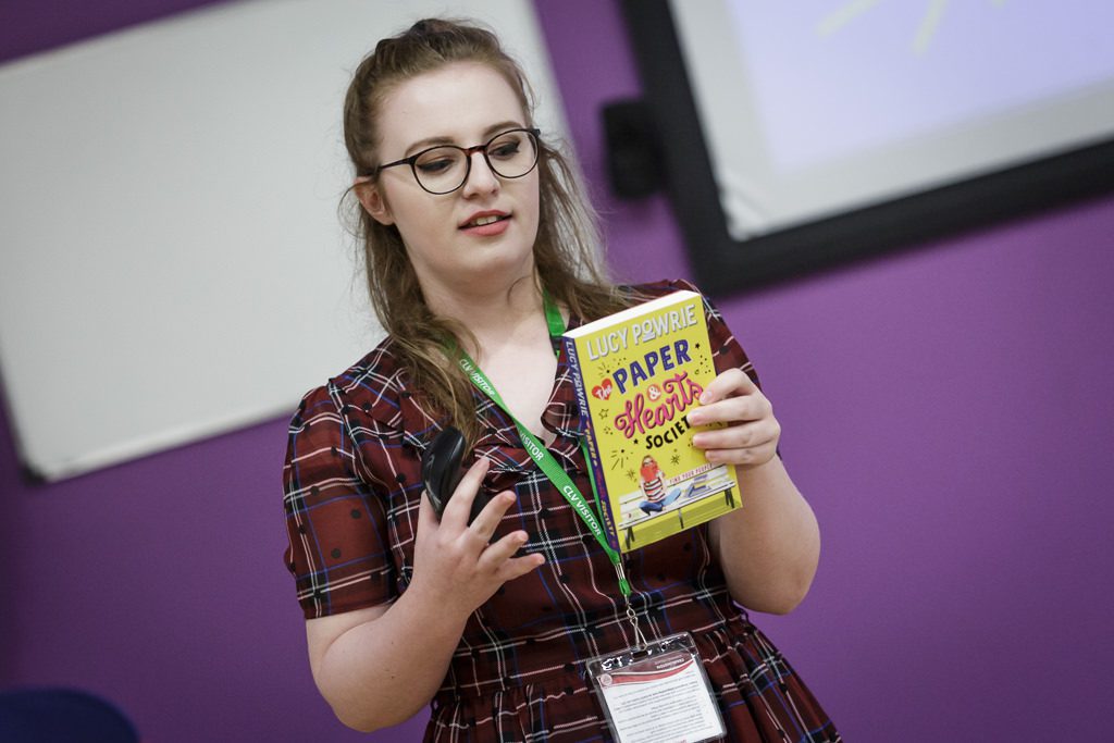 Image of author with her book talking to students