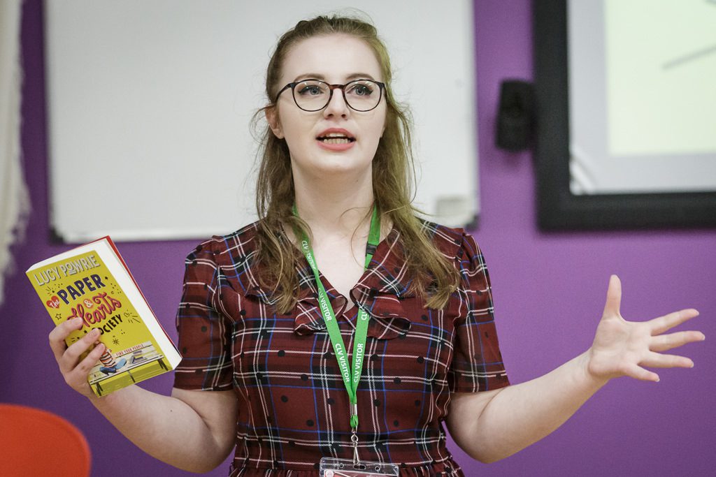 Image of author with her book talking to students