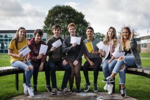 Students sitting on a bench looking happy with their exam results