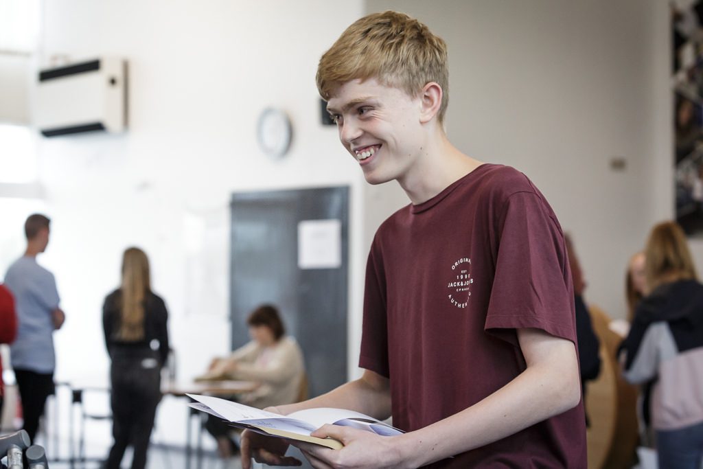 Student opening his exam results and looking very happy