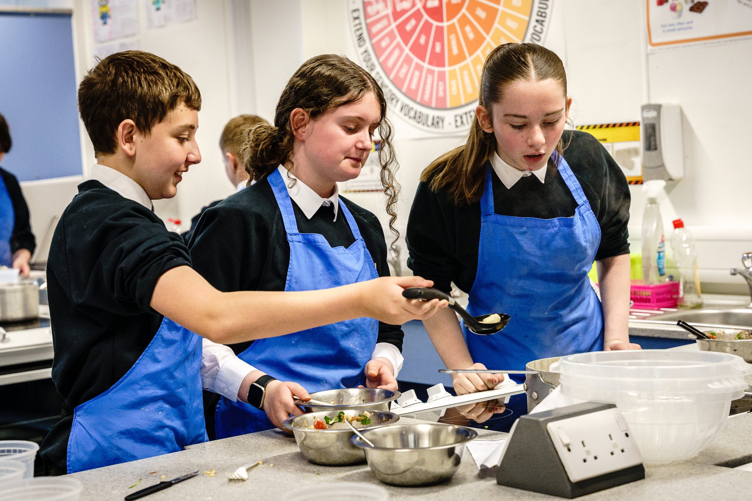 Student checking their pasta on the cooker hob